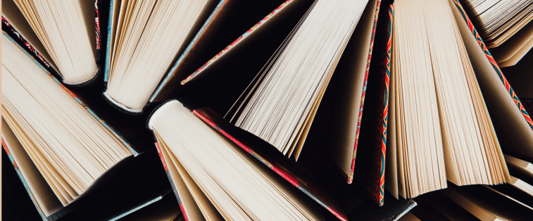 Vue en plongée sur des livres ouverts entassés, symbolisant la passion de la lecture et l’accumulation de romans