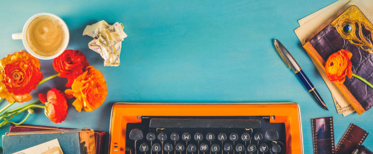 Machine à écrire vintage avec carnet, stylo et fleurs sur fond coloré – représentation du processus d’écriture d’un roman et de la créativité d’une autrice