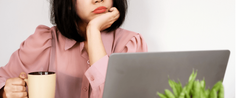 Femme pensive avec une tasse à la main devant un ordinateur portable, illustrant la recherche d’inspiration tard dans la nuit pour écrire un roman.